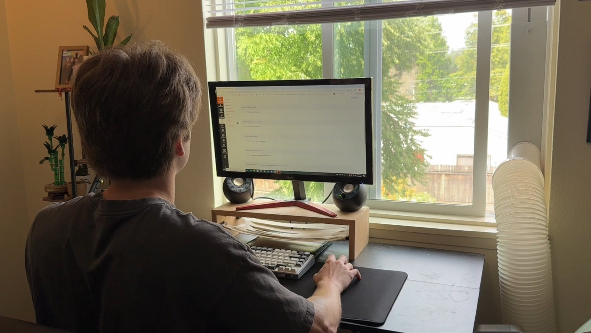 Completed wooden monitor stand with a woven storage hammock in use at a desk